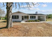 Charming single-story home with a white brick exterior, black shutters, and mature trees at 860 Main St, Lillington, NC 27546