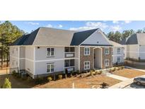 Inviting two-story apartment building featuring stone accents, grey siding, and well-manicured landscaping at 240 Gallery Dr # 102, Spring Lake, NC 28390