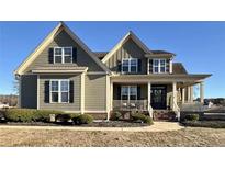 Charming craftsman-style home with light olive siding, black shutters and inviting front porch and manicured lawn at 42 Walnut Grove Dr, Bunnlevel, NC 28323