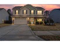 Charming two-story home with a stone and vinyl facade, covered porch, two-car garage, and landscaped yard at 190 National Dr, Clayton, NC 27527