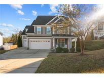 Charming two-story home featuring a well-maintained lawn, a two-car garage, and a cozy front porch with rocking chairs at 278 Bandana Way, Cameron, NC 28326