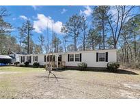 Charming single-story home featuring a spacious front yard and traditional design with black shutters and wood porch at 121 H B Dr, Spring Lake, NC 28390