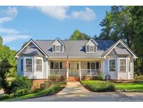 Charming single-story home featuring a metal roof, white siding, dormers, and a welcoming front porch at 609 Cashmere Ct, Sanford, NC 27332