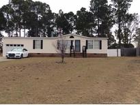 Charming single-story home with a manicured lawn and a car parked in front of the garage at 165 Brent Wood, Sanford, NC 27332