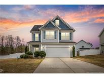 Charming two-story home featuring a well-manicured lawn and inviting curb appeal, set against a colorful sunset at 28 Coswell Ct, Cameron, NC 28326