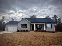 Charming single-story home with gray siding, black shutters, and a covered front porch at 4271 Mcdougald Rd, Lillington, NC 27546