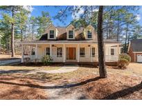 Charming home featuring a welcoming, full front porch with white columns and a beautiful wooded lot at 281 Pineridge Cv, Sanford, NC 27332