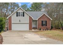 Charming two-story home featuring a brick and siding facade, attached garage, and inviting front yard with mature trees at 33 Woodbury Ln, Sanford, NC 27332