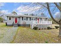 Charming single-story home featuring gray siding, black shutters, and a welcoming red front door at 148 Manchester Dr, Goldston, NC 27252