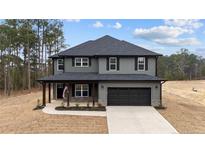 Two-story home with a two-car garage, gray siding, black shutters, covered porch and well manicured landscaping at 71 Persimmon Tree Dr, Cameron, NC 28326