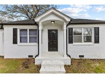 Charming white brick home featuring a covered entryway with black shutters and a stylish dark front door at 111 Spring Branch Rd, Dunn, NC 28334
