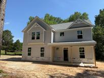 New two-story home with light gray siding, gabled roof, and covered front porch framed by mature trees on a sunny day at 1945 Cranes Creek Rd, Cameron, NC 28326