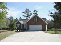 Charming brick home featuring a two-car garage, well-manicured lawn, and a long driveway at 42 Twin Ponds Rd, Sanford, NC 27332