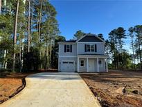 Two-story home showcasing light gray siding, black shutters, a single car garage, and covered porch nestled among tall trees at 187 Regis Ln, Coats, NC 27521