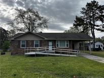 Charming single-story brick home with a ramp leading to the front door and a covered carport at 107 Mars Dr, Dunn, NC 28334