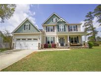 Charming two-story home featuring a manicured lawn, a covered front porch, and a two-car garage at 126 Islay Dr, Cameron, NC 28326
