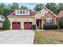 Charming home featuring a stone facade, inviting front porch, two-car garage, and manicured landscaping at 758 Micahs N Way, Spring Lake, NC 28390