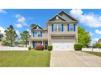 Lovely two-story home with a manicured lawn, blue shutters, a two-car garage, and mature trees at 148 Huzzas Cir, Cameron, NC 28326