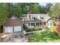 Charming brick home featuring a welcoming front porch, a two-car garage, and landscaped front yard at 8042 Royal Dr, Sanford, NC 27332