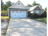 Charming single-story home featuring a spacious driveway and attached two-car garage at 223 Angel Oak Dr, Bunnlevel, NC 28323