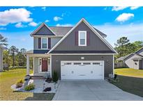 Charming two-story home featuring a gray exterior, double garage, landscaped yard and inviting front porch at 254 Angel Oak Dr, Bunnlevel, NC 28323