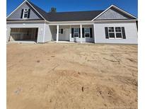 Charming single-story home featuring light gray siding, black shutters, and an attached two-car garage at 66 Blackgum Ct, Spring Lake, NC 28390