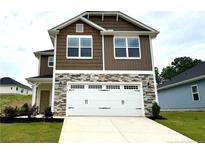 Two-story home with a two-car garage, mixed stone and vinyl siding, and a well-manicured lawn at 316 Bishop Ln, Sanford, NC 27330
