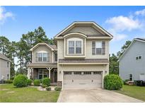 Charming two-story home boasts a manicured lawn, stone accents, and an attached two-car garage at 852 Micahs N Way, Spring Lake, NC 28390