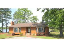 Charming single-story home featuring a brick chimney, lakeside views, and landscaped yard at 104 Cove Landing, Sanford, NC 27332