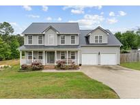Charming two-story home with a metal roof, a welcoming front porch, and a well-manicured lawn at 70 Mountainside Ln, Sanford, NC 27332