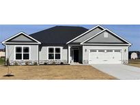 Charming single-story home featuring a well-manicured lawn, gray siding, and a bright white garage door at 21 Shoreline Dr, Lillington, NC 27546