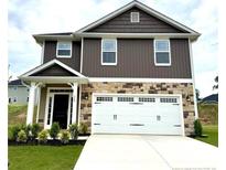 Charming two-story home featuring stone accents, a two-car garage, and beautifully landscaped front yard at 320 Bishop Ln, Sanford, NC 27330