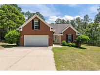 Charming brick home featuring a manicured lawn, attached garage, and a welcoming entrance at 481 Clearwater Hbr, Sanford, NC 27332