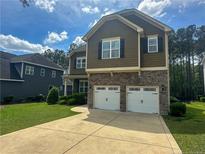 Charming home featuring a stone and siding facade, two-car garage, and manicured lawn at 109 Valley Brook Ln, Spring Lake, NC 28390