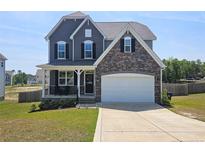 Charming two-story home featuring stone accents, a two-car garage, and a well-maintained front yard with landscaping at 334 Bunting Dr, Lillington, NC 27546