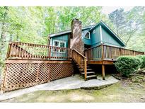 Charming home with a large wooden deck, brick chimney, and light blue siding, surrounded by mature trees at 416 Harbor Trce, Sanford, NC 27332