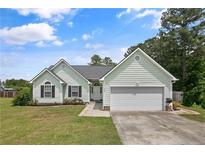Charming single-story home featuring light green siding, a two-car garage, and a well-maintained front yard with a concrete driveway at 708 Overhills Rd, Linden, NC 28356