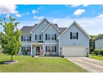 Charming two-story home with light blue siding, black shutters, a green lawn, and an attached two-car garage at 101 Shepard Dr, Linden, NC 28356