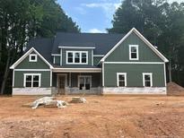 New two-story home featuring vertical siding, a dark roof, white trim, and traditional windows at 194 Landon Rdg, Sanford, NC 27330