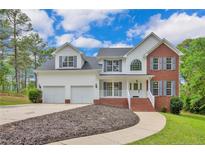 Charming two-story home features a brick and vinyl exterior, attached garage, and landscaped front yard at 569 Yorkshire Dr, Cameron, NC 28326