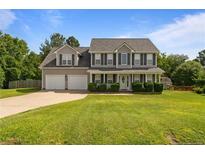 Charming two-story home with a well-manicured lawn and a two-car garage on a sunny day at 11 Checkmate Ct, Cameron, NC 28326