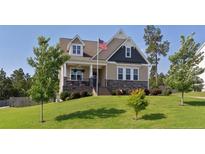 Charming two-story home featuring an American flag, covered porch, landscaped yard, and stone accents at 556 Executive Dr, Lillington, NC 27546