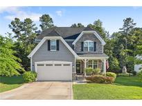 Charming two-story home with gray siding, stone accents, two-car garage and well-manicured lawn at 102 Scholar Dr, Spring Lake, NC 28390