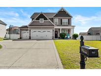 Charming two-story home featuring a three car garage and well-maintained lawn at 123 Tun Tavern Dr, Cameron, NC 28326