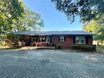 Charming single-story brick home featuring a metal roof, front porch, and neatly trimmed shrubs at 12558 Mcdougald Rd, Broadway, NC 27505
