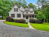 Charming two-story home features a covered front porch, manicured lawn, and a gravel driveway at 635 Buckroe Dr, Sanford, NC 27330
