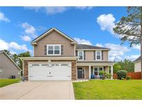 Charming two-story home featuring a two-car garage, a well-manicured lawn and a welcoming front porch at 104 Parkview Ln, Lillington, NC 27546