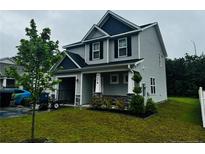 Charming two-story home with gray siding, stone accents, a well-maintained lawn, and attached garage at 4179 Overhills Rd, Spring Lake, NC 28390