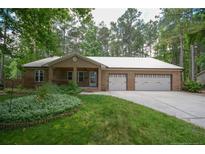 Charming brick home featuring a two-car garage, well-maintained lawn, and cozy front porch at 129 Silver Lake Pt, Sanford, NC 27332
