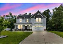 Charming two-story home with a well-manicured lawn and a welcoming front porch at dusk at 186 Old Glory Ln, Cameron, NC 28326